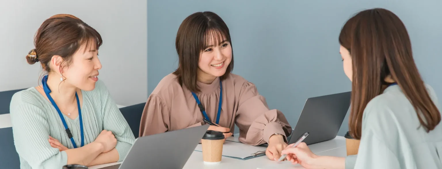 会社で笑顔で会話する女性たち